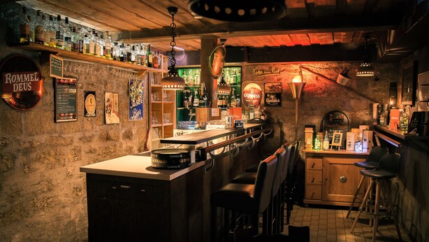 Eine Bar mit rustikalem Interieur, Holzböden mit Flaschen, einer Bar, Hockern und einer Kreidetafel-Speisekarte.
