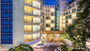 Een hotel met meerdere verdiepingen, balkons, een binnenplaats met terras en een parkeerplaats.