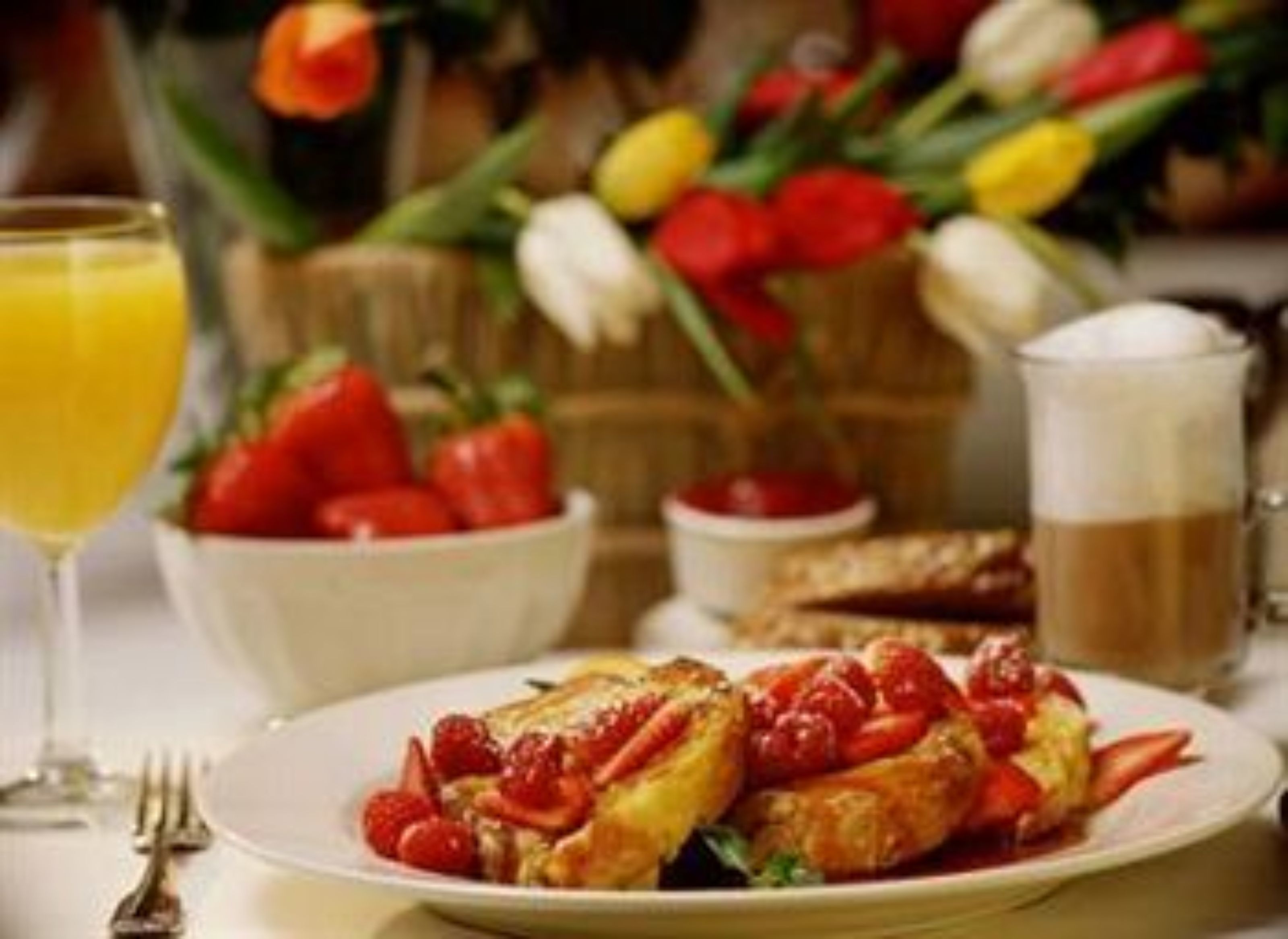 A breakfast setting with a plate of food, a glass of orange juice, and a cup of coffee.