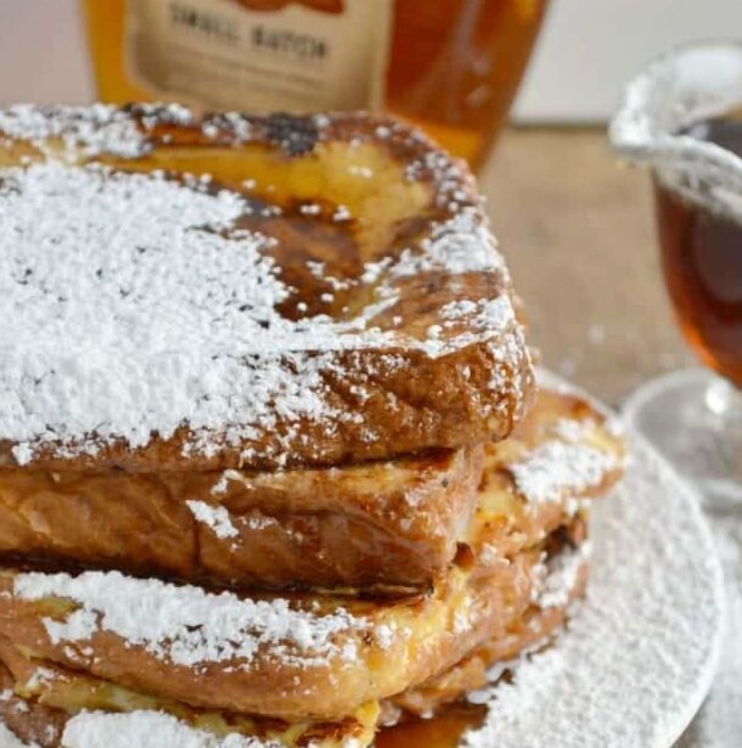 A stack of pancakes with powdered sugar on a plate.