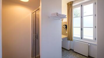 Une salle de bain avec une douche, des toilettes, un lavabo et une fenêtre avec des rideaux.
