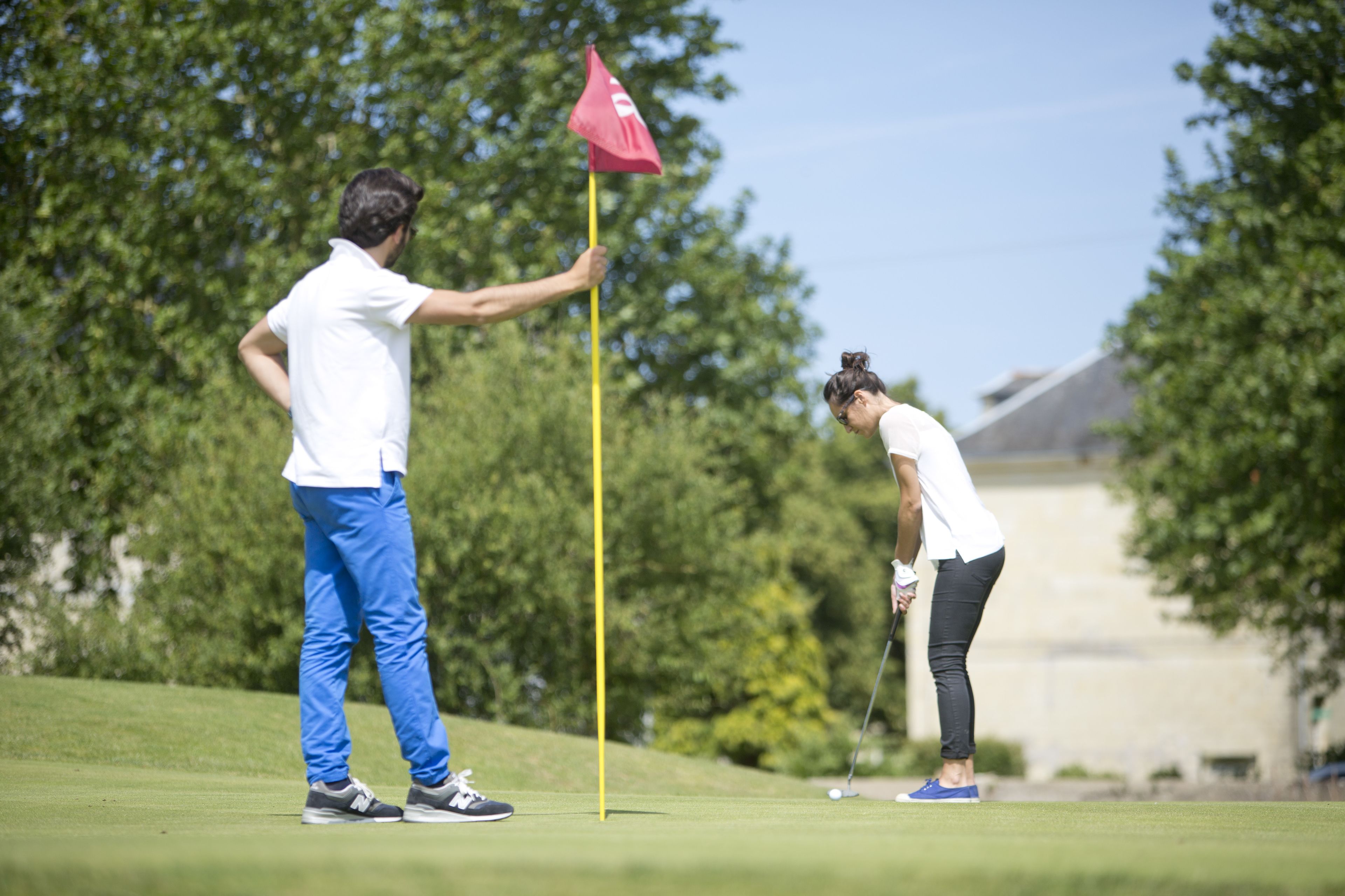 A golf course with a flagstick and players.