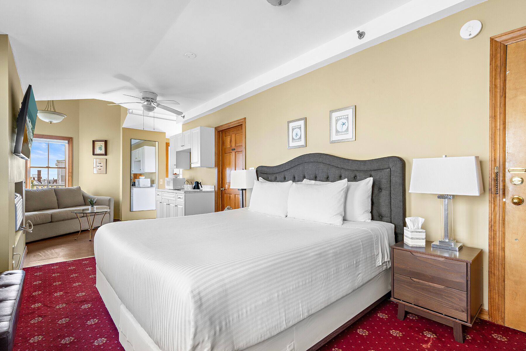 Camera d'albergo con un letto grande, un divano, una scrivania e un angolo cottura.
