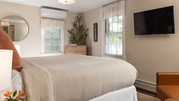 Un dormitorio con una cama grande, un televisor de pantalla plana, un aparador y una ventana con cortinas.