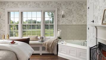 A bedroom with a large window, a bed, a nightstand, a dresser, and a fireplace.