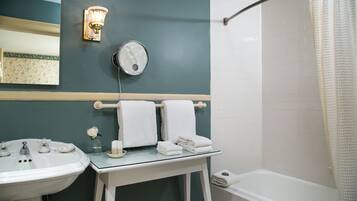 A bathroom with a sink, mirror, and a glass-topped vanity with towels.