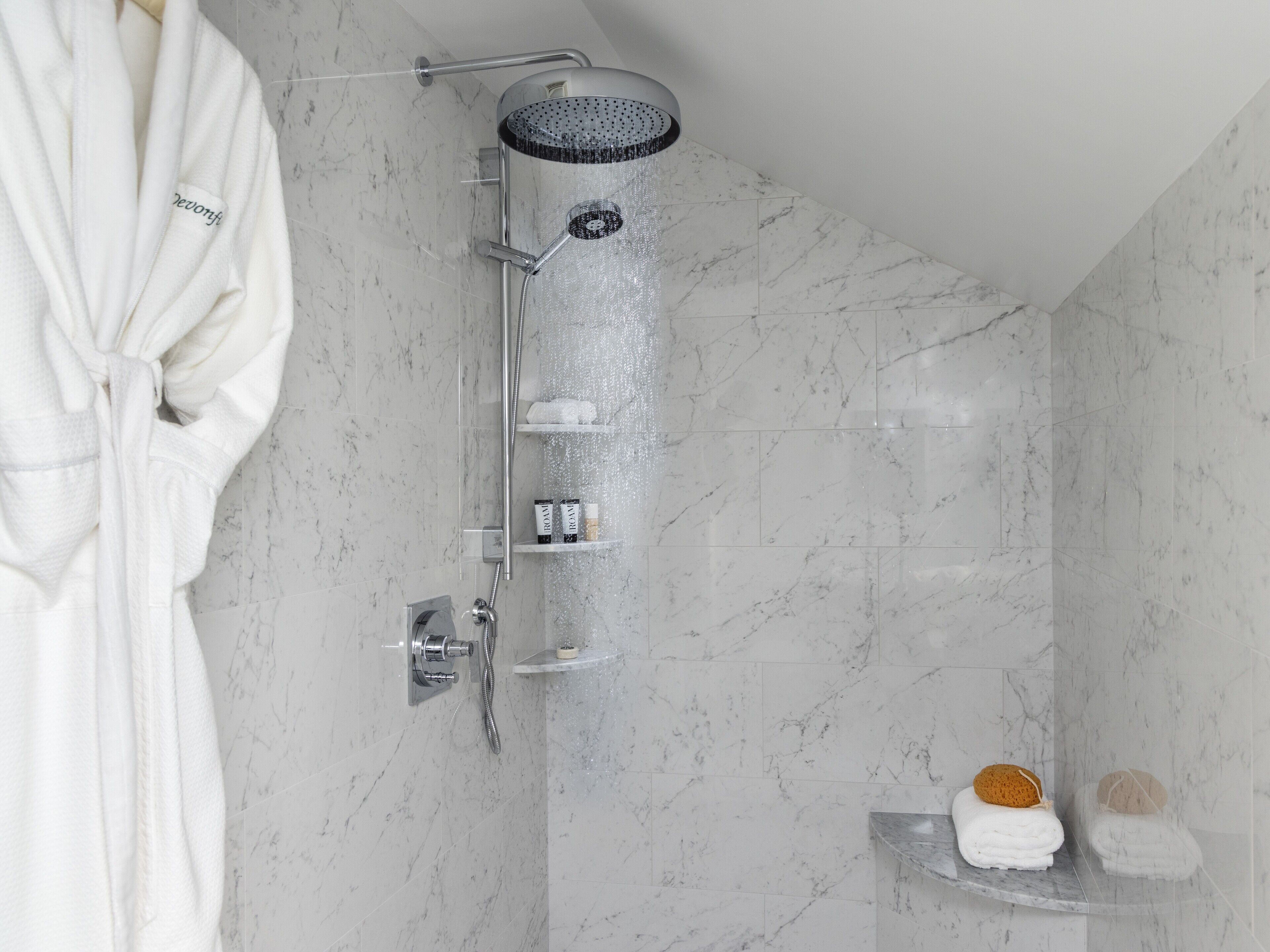 A modern bathroom with a shower, marble tiles, and a towel rack.
