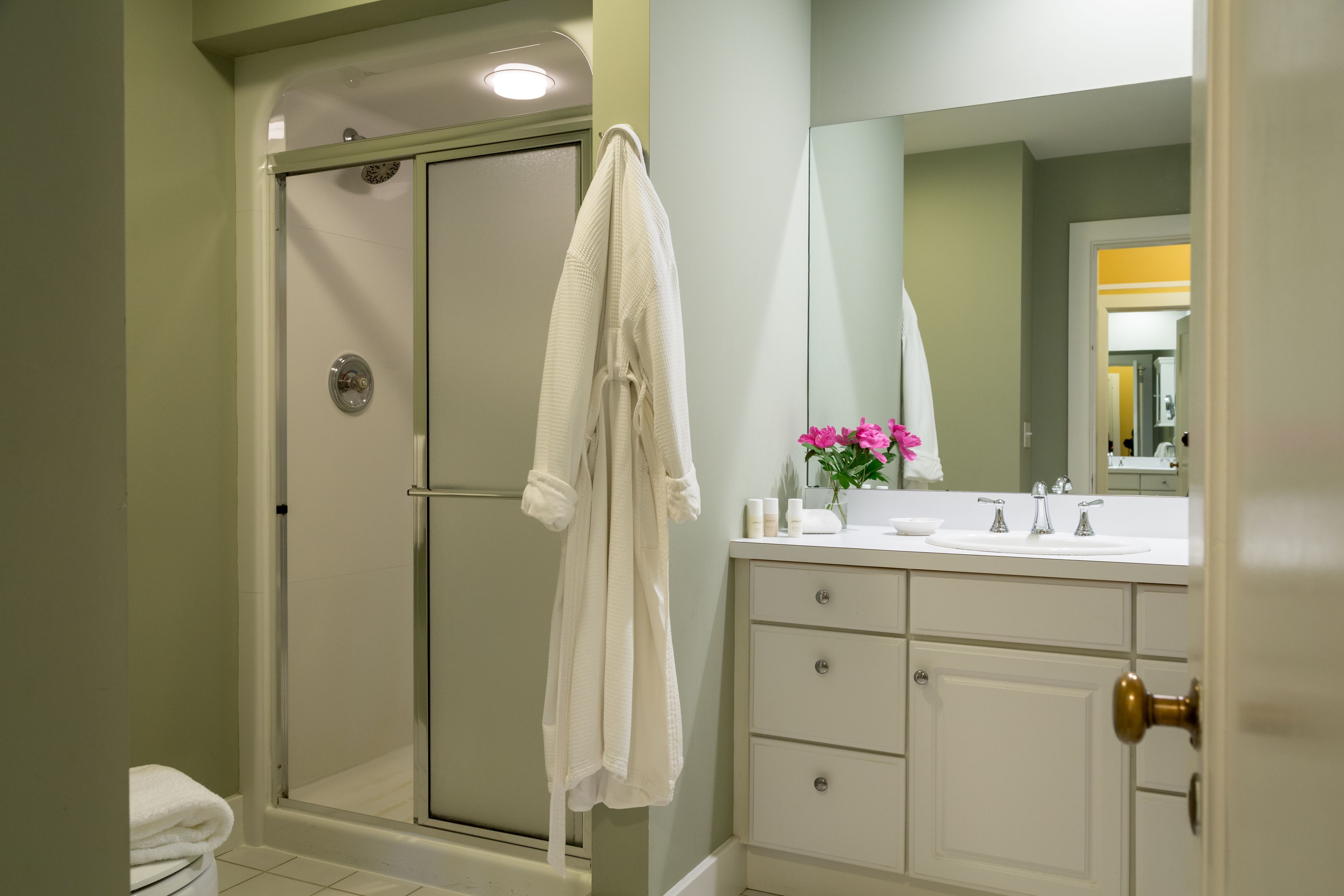 A bathroom with a glass-enclosed shower, a white vanity with a mirror, and a towel rack.