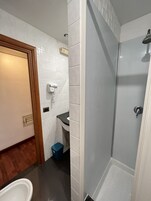 Uma casa de banho com chuveiro, sanita e lavatório.