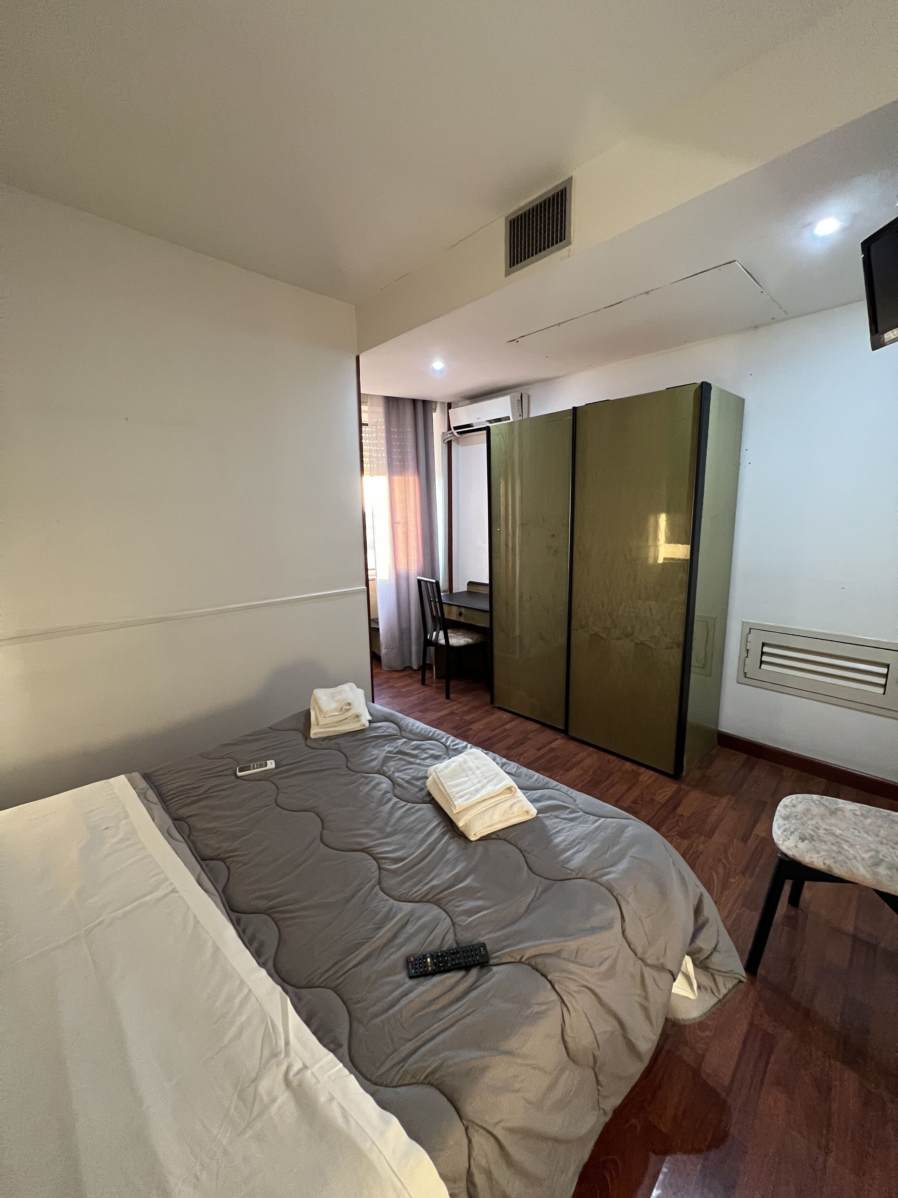 Een hotelkamer met een bed, een stoel, een bureau en een kledingkast.