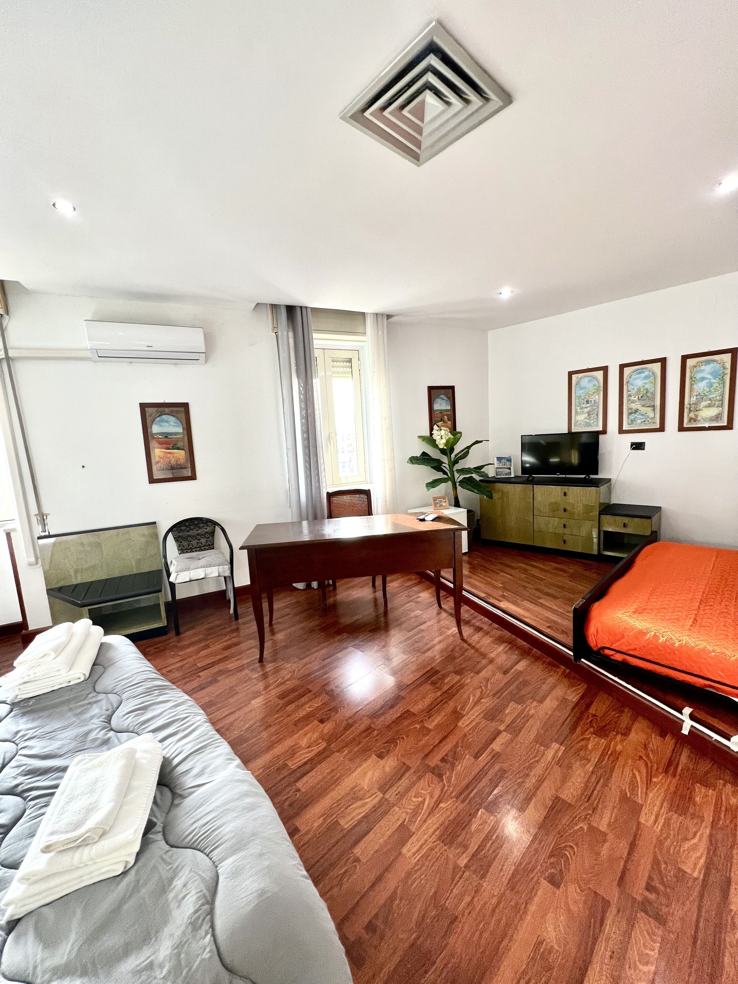 Una habitación de hotel con cama, escritorio, silla, mesa de comedor y televisor.