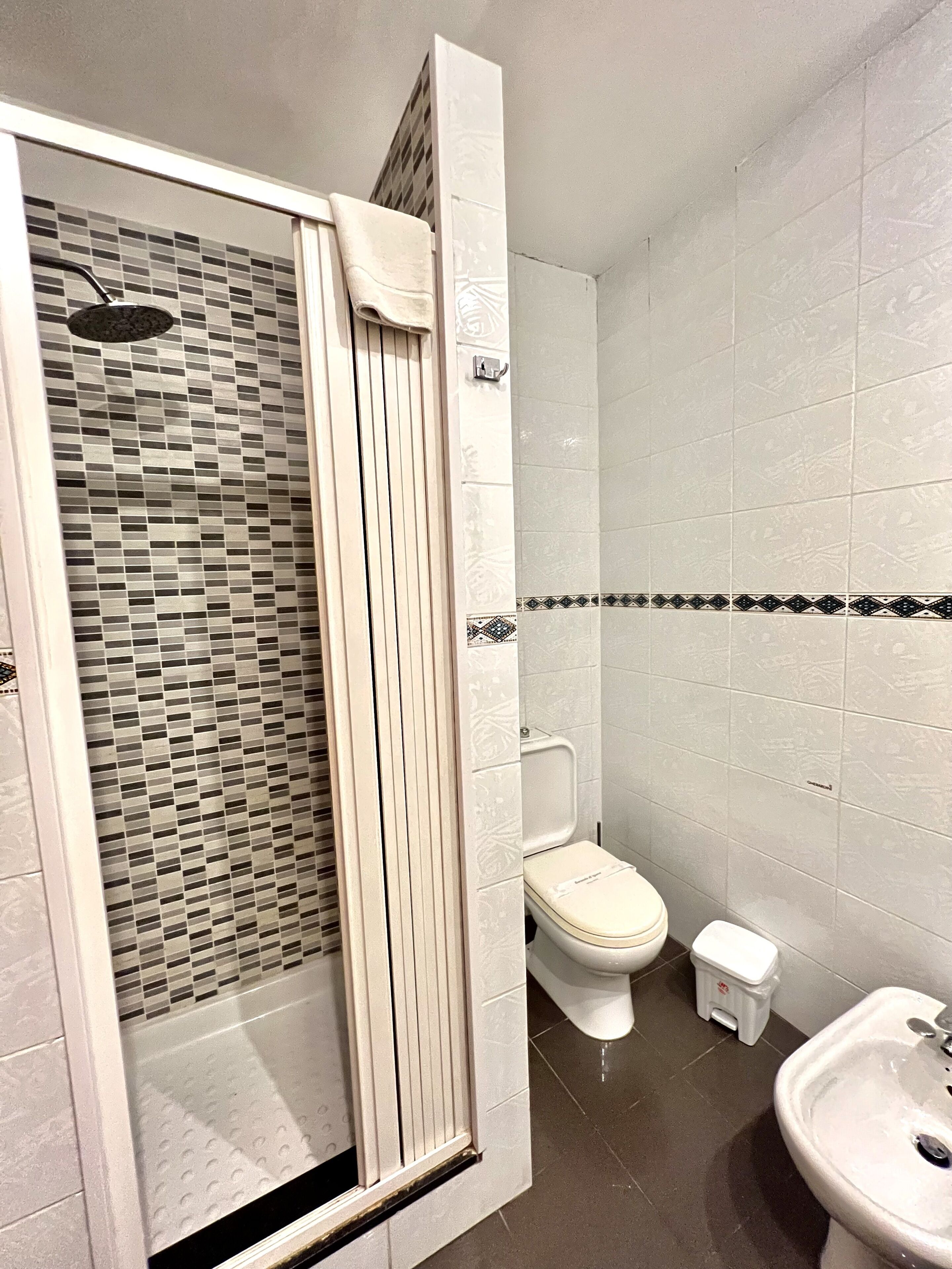 A bathroom with a shower, toilet, and sink.