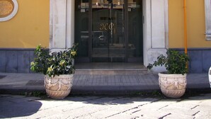 A hotel entrance with a sign reading "Hotel Como" and three flags. - Hotel Como (Syracuse)