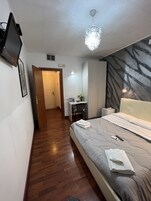Habitación de hotel con cama, escritorio, silla, televisión y una lámpara decorativa.