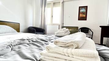 Una camera d'albergo con un letto, una sedia, una scrivania e una finestra con tende.