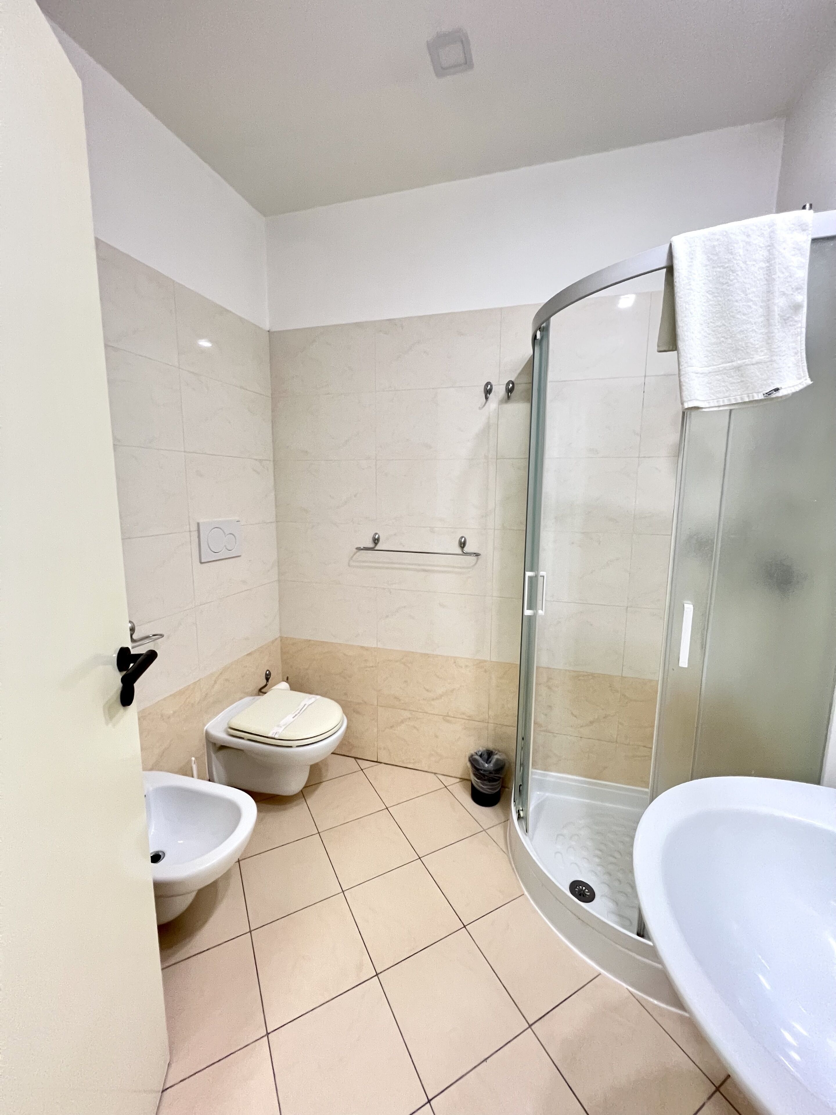 Un baño con ducha de mampara, inodoro y dos lavamanos.