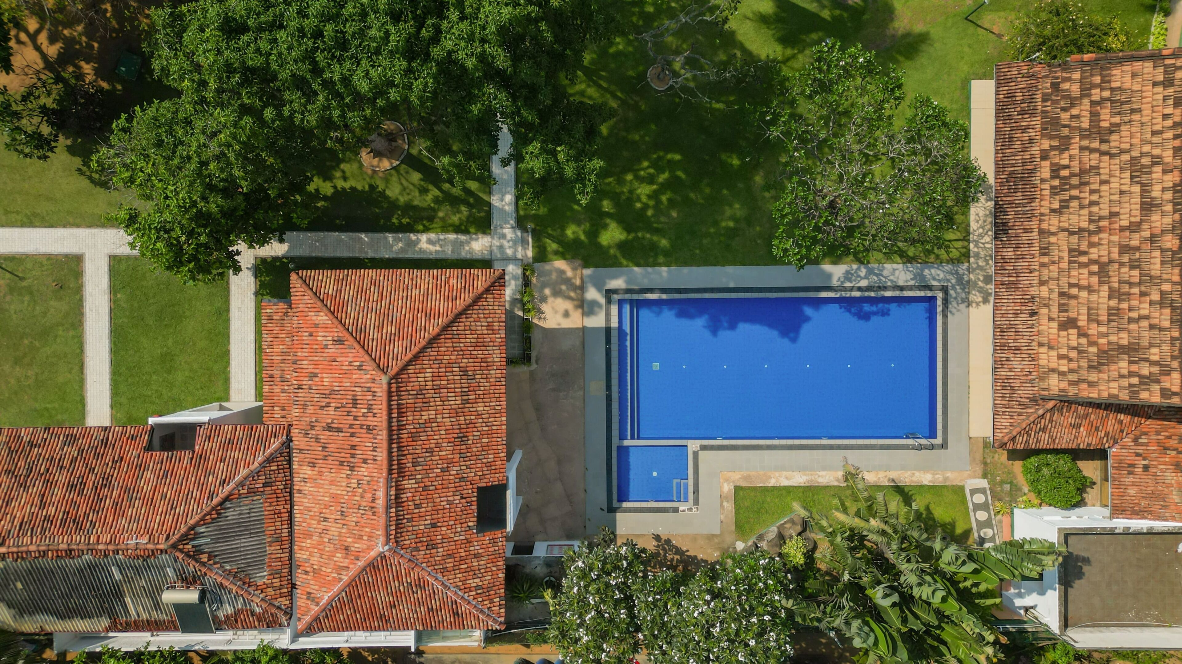 Vue aérienne d’un quartier résidentiel avec une piscine, des bâtiments en briques et de la végétation environnante.