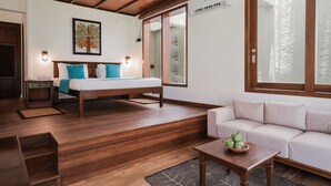 A room with a bed, a sofa, a wooden floor, a window, and a wall-mounted air conditioner. - Hibiscus Beach Hotel And Villas (Wadduwa)