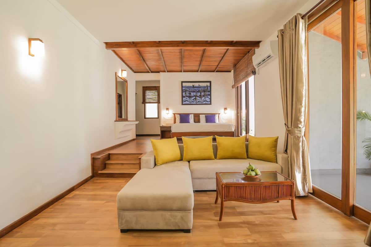 Ein modernes Wohnzimmer mit Sofa, Hocker und Couchtisch, Holzboden und einer Treppe zu einem anderen Raum.