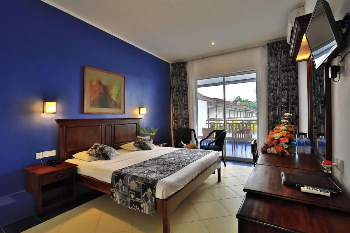 Ein Hotelzimmer mit Bett, Schreibtisch, Stuhl, Fernseher und einem Balkon mit Blick.