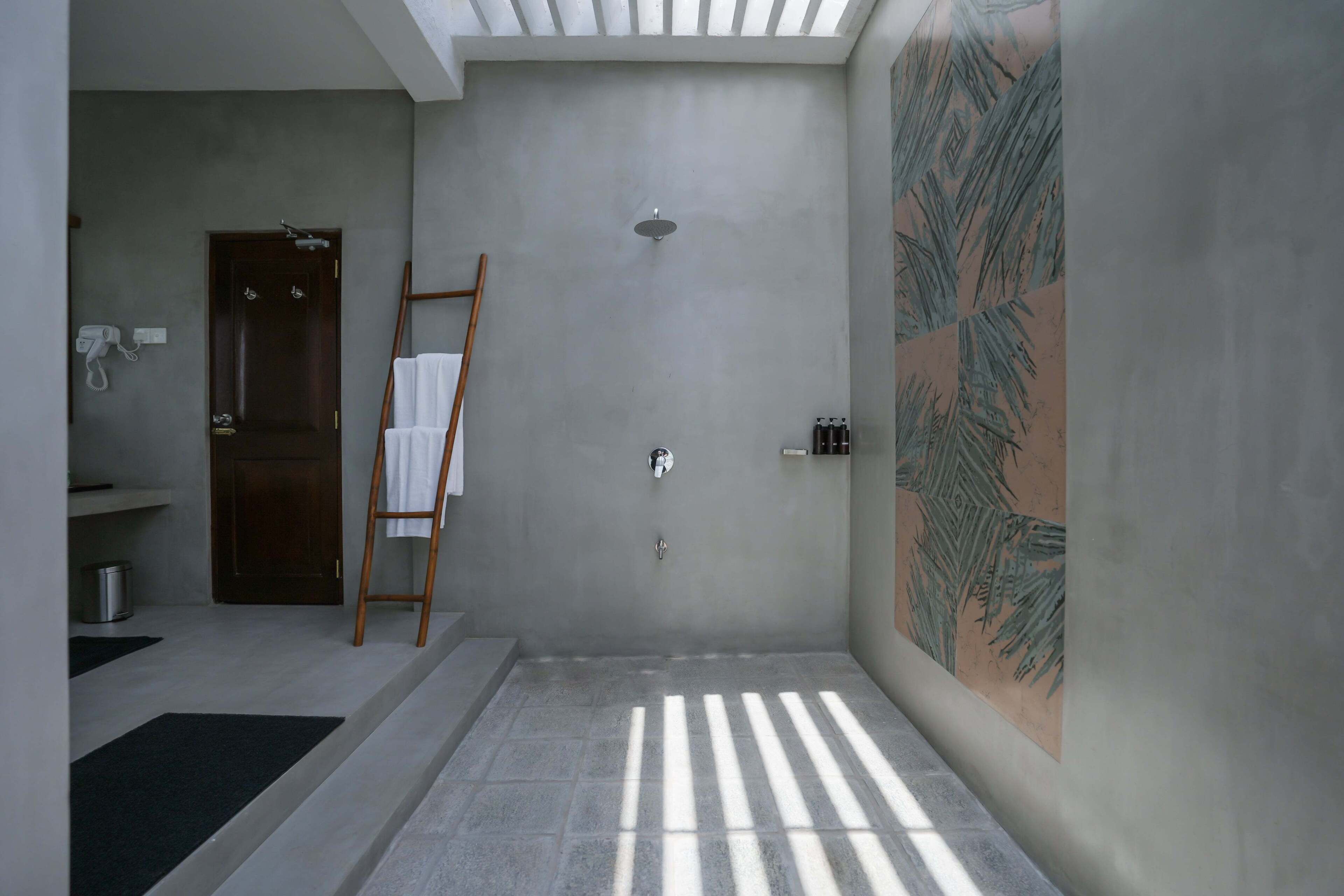 A modern bathroom with a shower, a towel rack, and a wooden ladder.