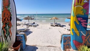Une plage avec des planches de surf, des chaises de plage et des parasols.