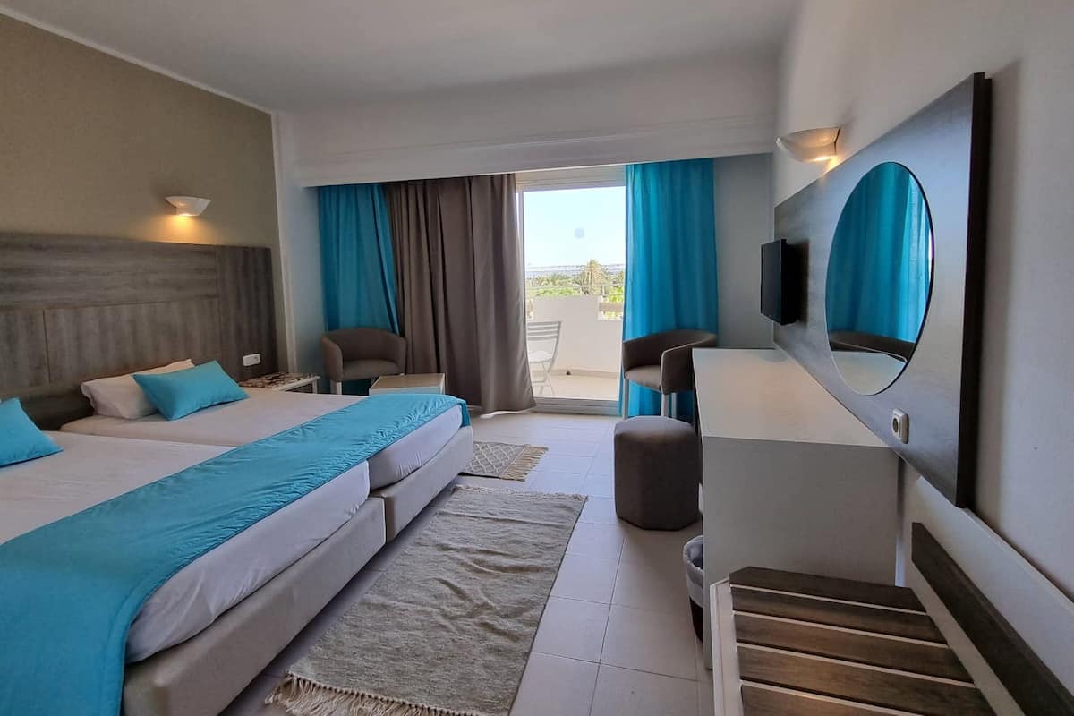 Une chambre d’hôtel avec deux lits, une télévision, un bureau et une vue sur l’extérieur.