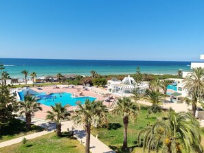 A resort with a large pool, palm trees, and a view of the ocean. - Helya Beach Resort (Monastir)