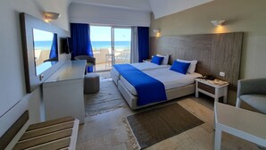 Une chambre d’hôtel avec un grand lit, un bureau, une chaise et une télévision. Elle dispose d’un balcon avec vue sur l’océan.