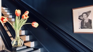 A staircase with a vase of tulips on a black console table.