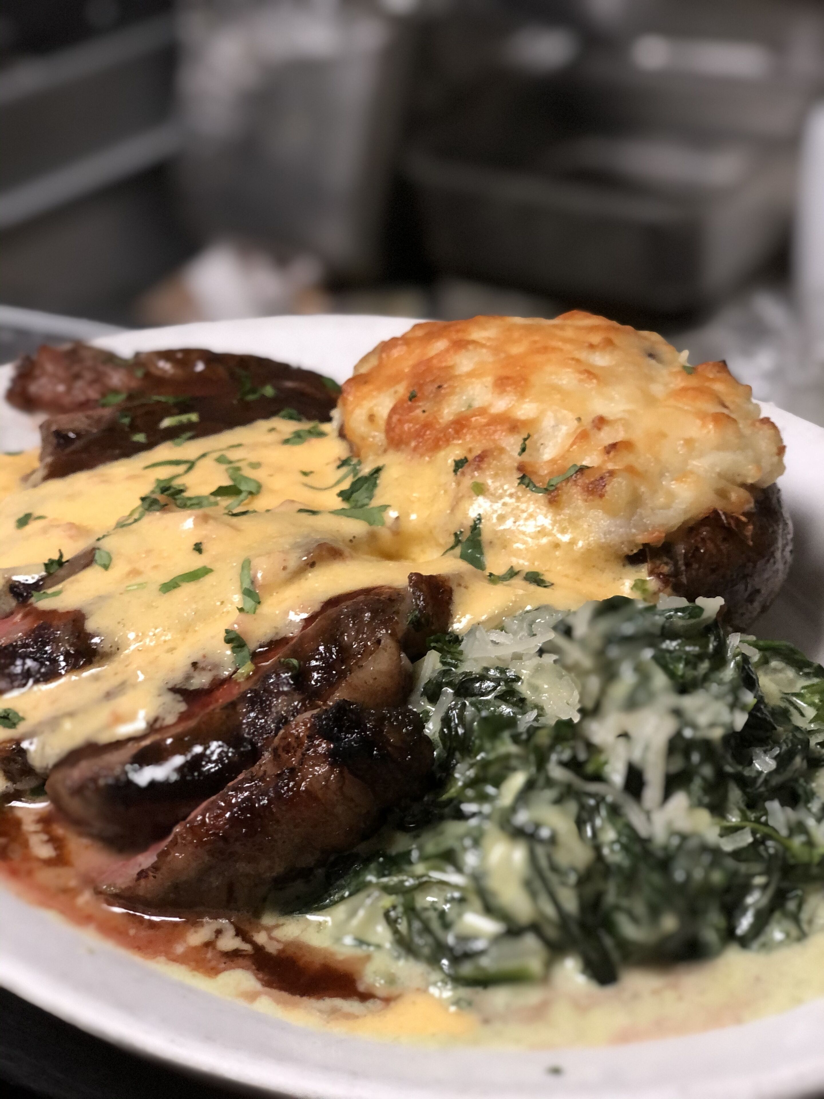 Un plato de comida con puré de papas, carne y vegetales verdes.