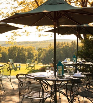 Enjoy al fresco dining under the shade of a large umbrella, surrounded by a serene forest landscape.