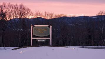 A Chesterfield Inn sign with a directional arrow beneath it, surrounded by a snowy landscape and trees.