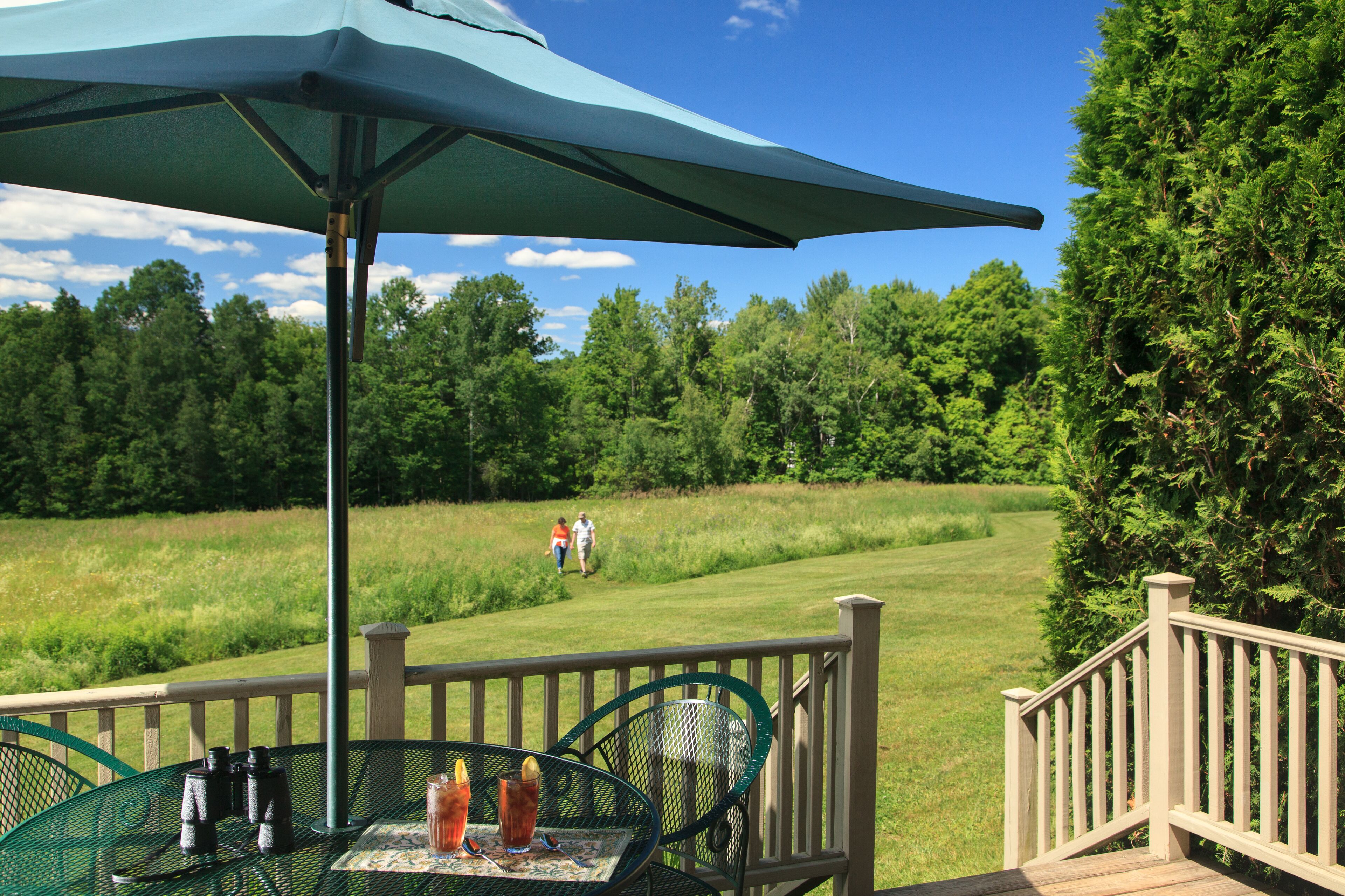 Une terrasse avec une table et des chaises, des jumelles et une boisson.