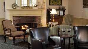A cozy living room with a fireplace, leather chairs, a sofa, and a table with wine glasses. - Chesterfield Inn (West Chesterfield)