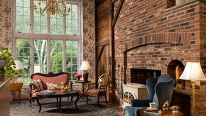 A cozy room with a brick fireplace, floral wallpaper, and comfortable seating. - Chesterfield Inn (West Chesterfield)