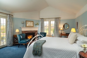 Relax in this inviting bedroom with a large bed, two chairs, and a fireplace.