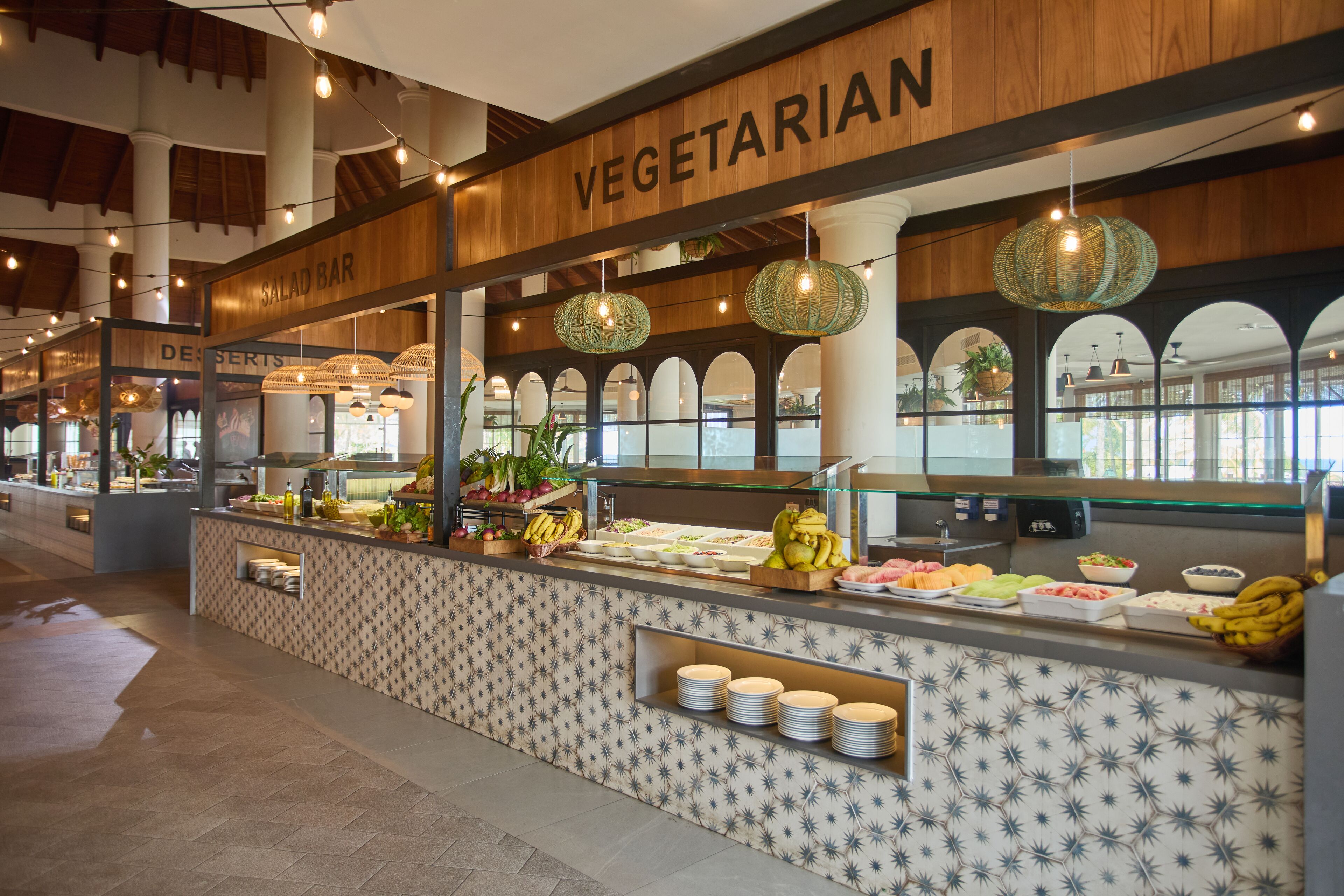 Zona de bufé con sección vegetariana, barra de ensaladas y mesa de postres.