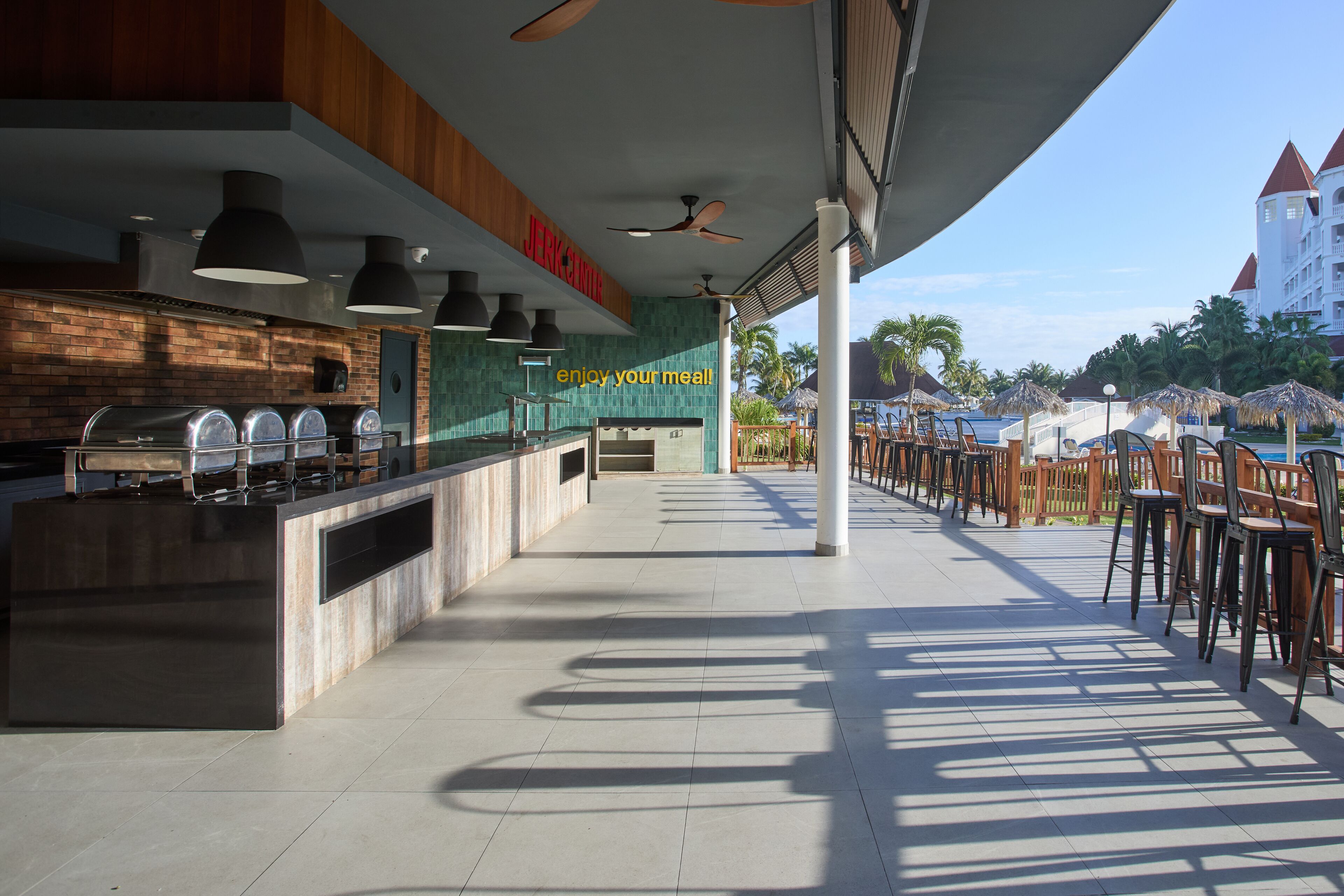 A modern outdoor dining area with a brick wall, a counter with a grill, and a sign that reads "JERUSALEM".