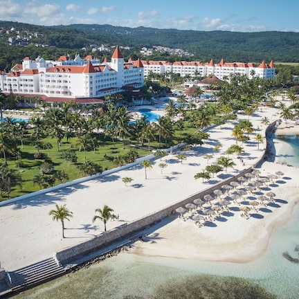 A resort with multiple white buildings, a beach, and a pool area.