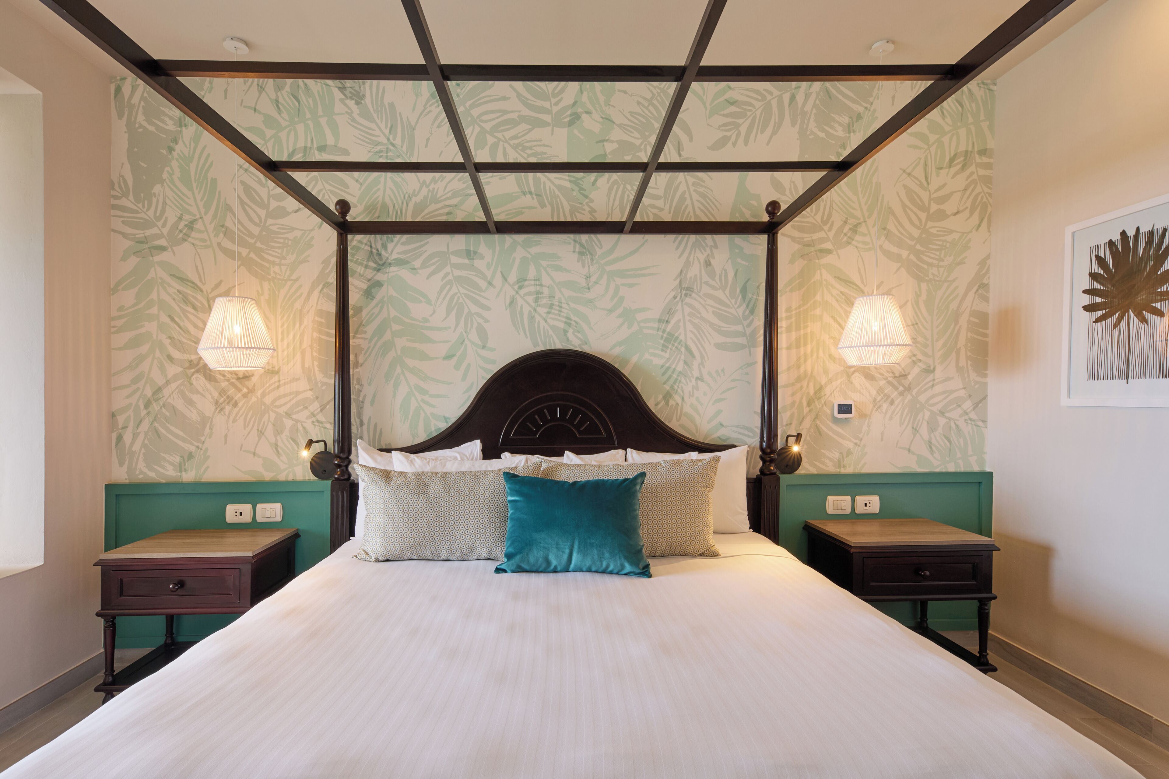 A four-poster bed with a headboard, two bedside tables, and wall-mounted lamps.