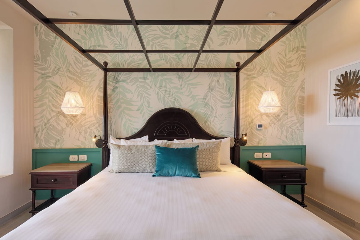 A four-poster bed with a headboard, two bedside tables, and wall-mounted lamps.