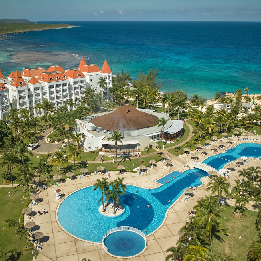 A resort with multiple swimming pools, a beach, and a view of the ocean.