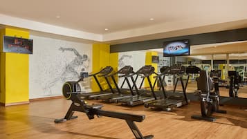 A gym with treadmills, stationary bikes, and a rowing machine.