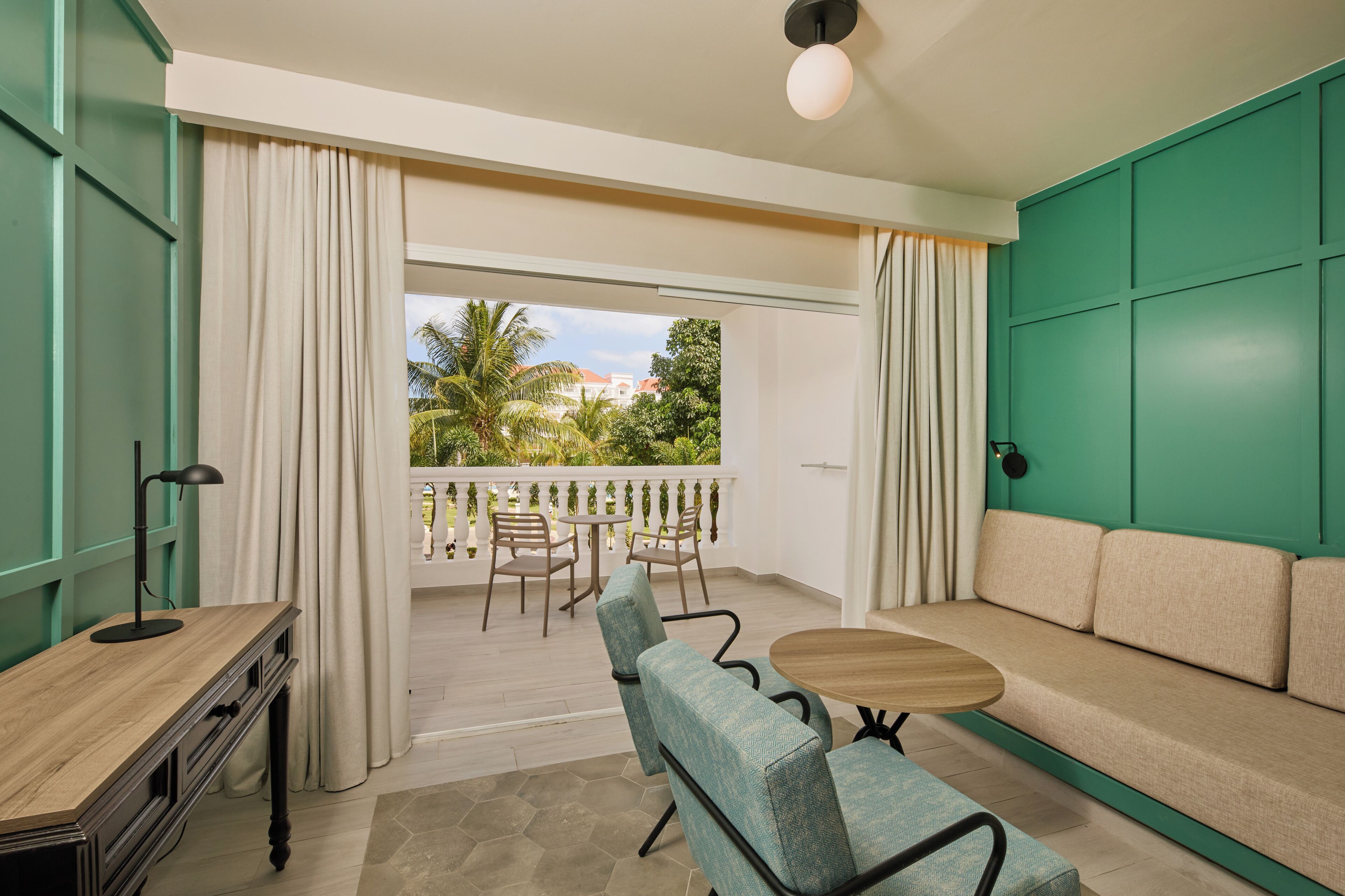 A balcony with a sofa, chairs, a table, and a lamp.