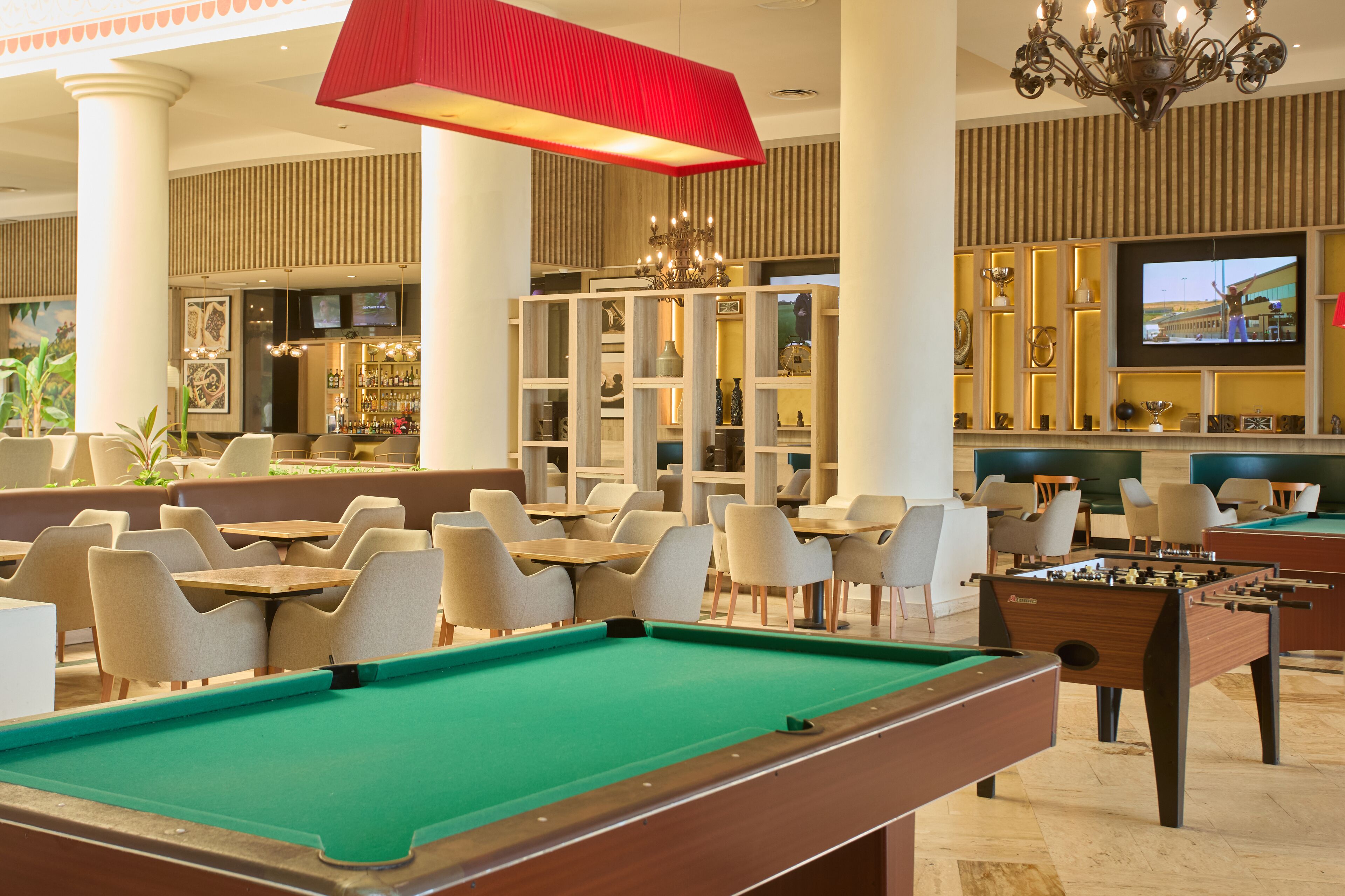 A pool table, seating area, and foosball table in a hotel lobby.
