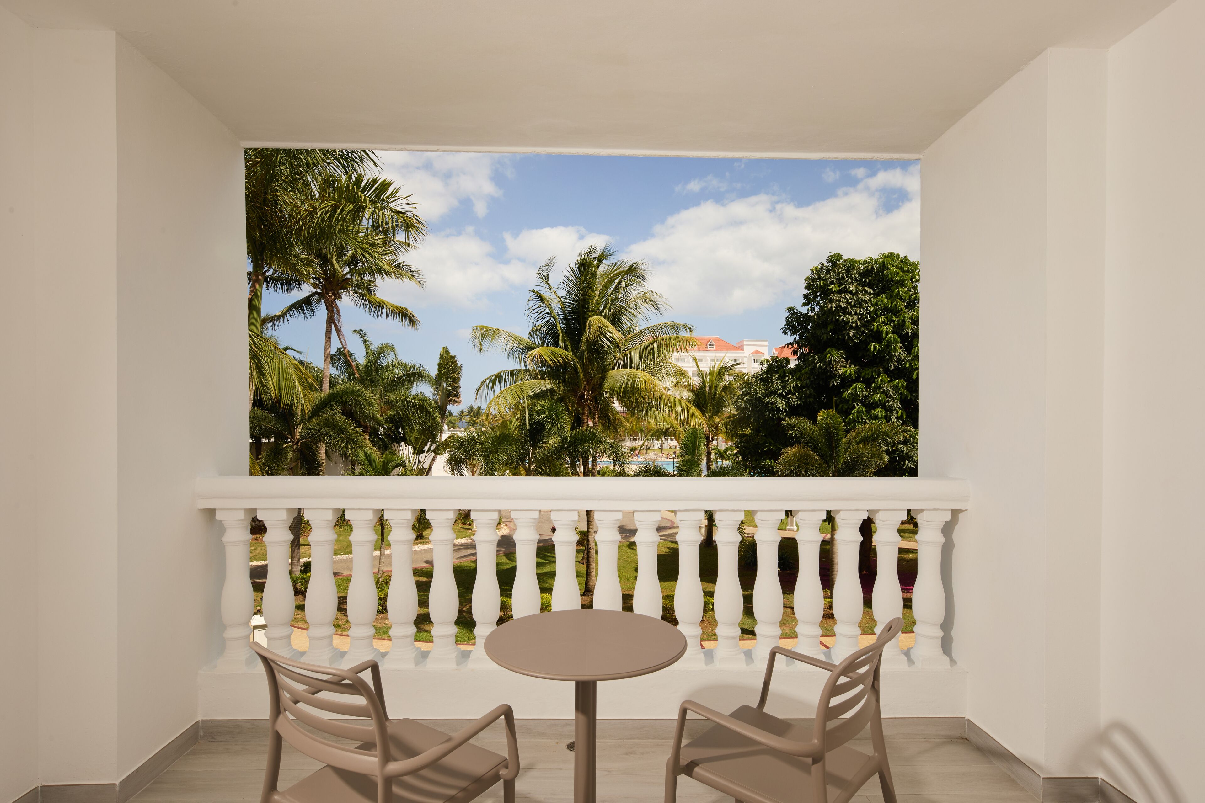 Un balcon doté d’une balustrade blanche, de deux chaises et d’une table ronde.