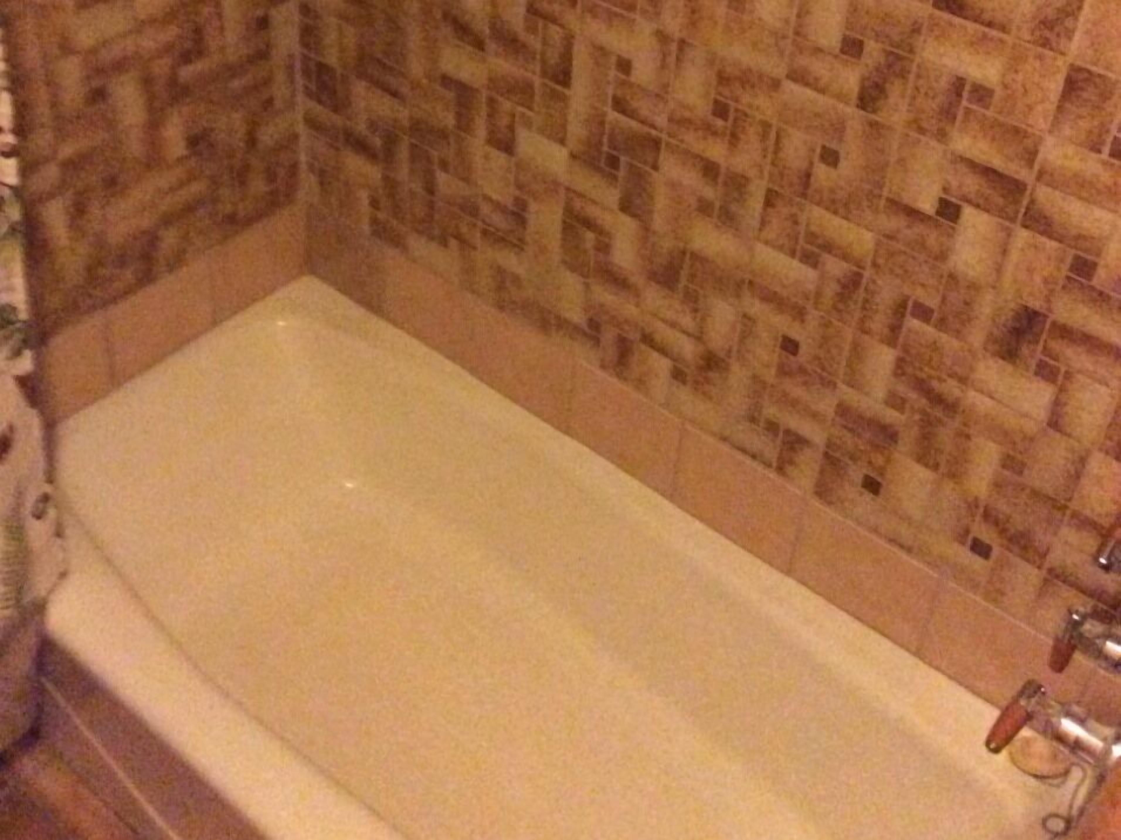 A bathroom with a bathtub, tiled walls, and a shower area.