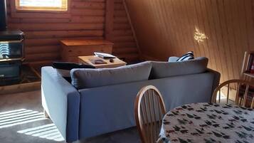 Una habitación acogedora tipo cabaña de madera con un sofá, una mesita y una silla.