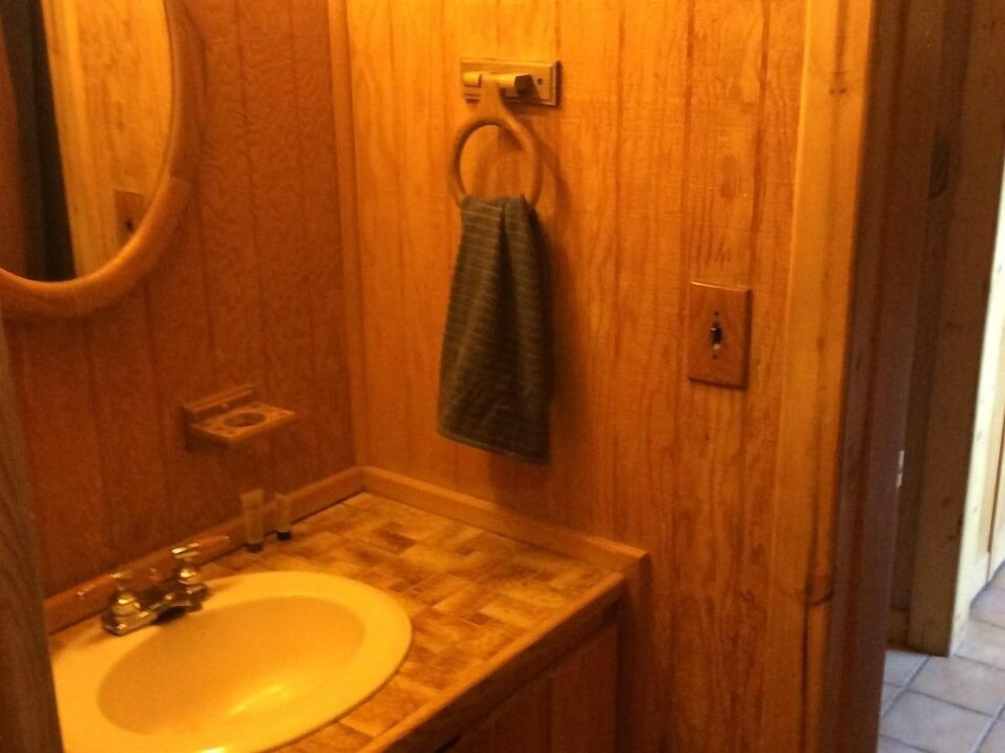 A bathroom with a wooden vanity, a sink, and a towel hanging on a ring.